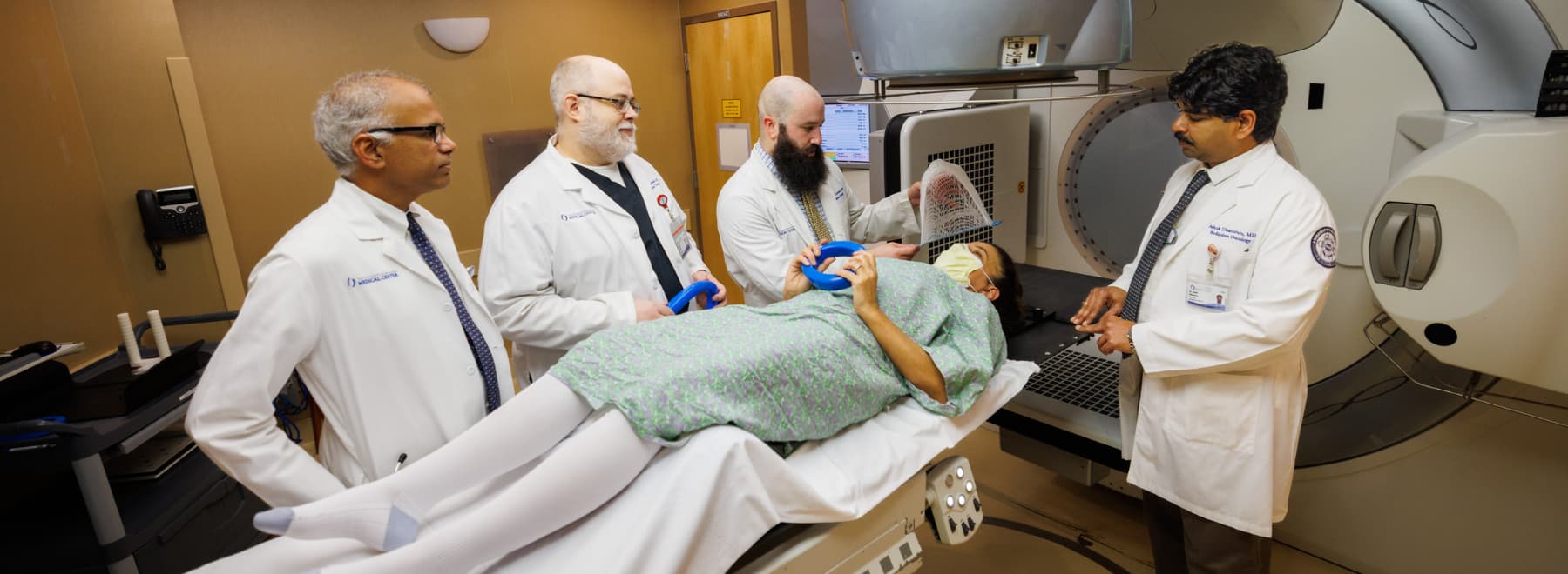 Four radiation oncologists work with a patient. Four radiation oncologists work with a patient.
